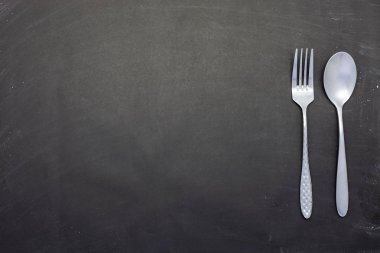 Paslanmaz çelik kaşık ve çatal siyah ahşap veya tebeşir tahtası 