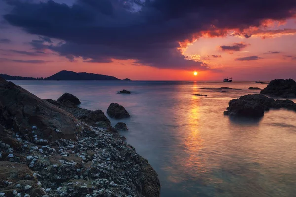 Lange blootstelling beeld van dramatische hemel zeegezicht met rock in de zonsondergang — Stockfoto