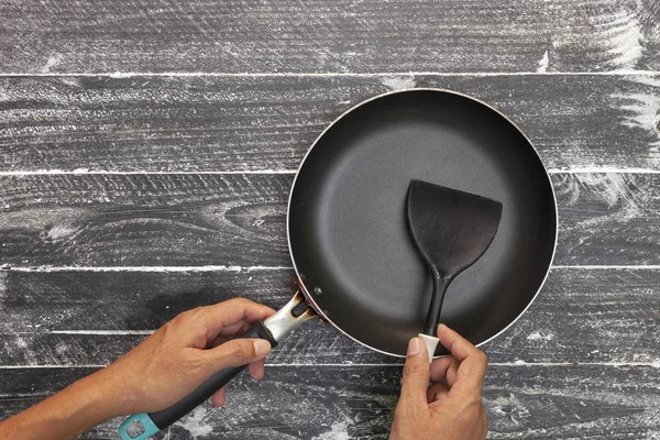 黒い木製の黒いへらで調理鍋を保持する手 — ストック写真