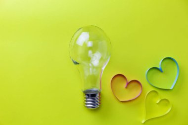 Sarı kağıt arka plan üzerinde kalp kurdele ile ampul