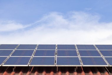 Kırmızı çatı mavi gökyüzünde güneş paneli ve güneş enerjisi paneli 