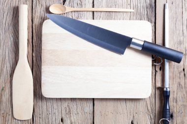 Eski ahşap masa arkasında mutfak gereçleri olan bıçak ve bileyici.