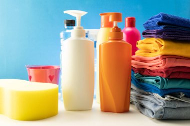 Masa arkasında renkli giysileri olan plastik temizlik ürünleri şişeleri.