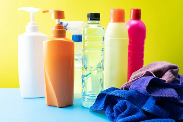 Masa arkasında üst üste yığılmış plastik temizlik ürünleri seti