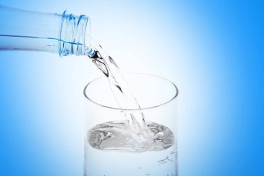 Plastik şişeden beyaz zemin üzerine cam dökülen su