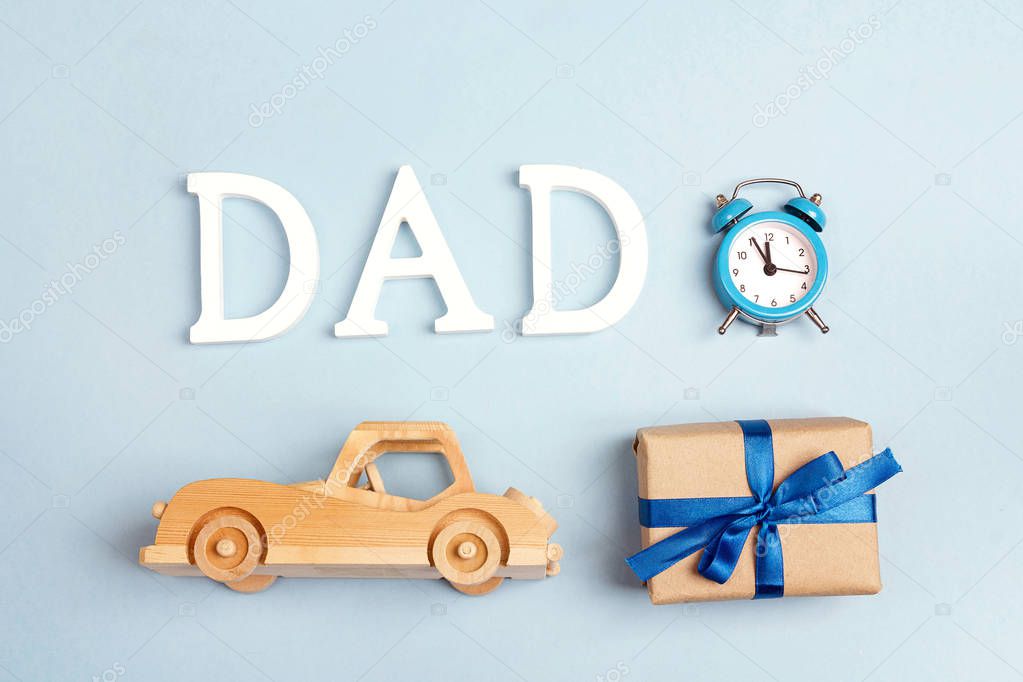 Fathers day background with wooden toy car, gift box, alarm clock and  letters dad. Happy fathers day concept