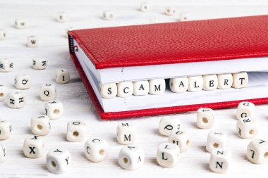 Kırmızı defter ahşap bloklar halinde wh üzerinde yazılı ifade Scam Uyarısı