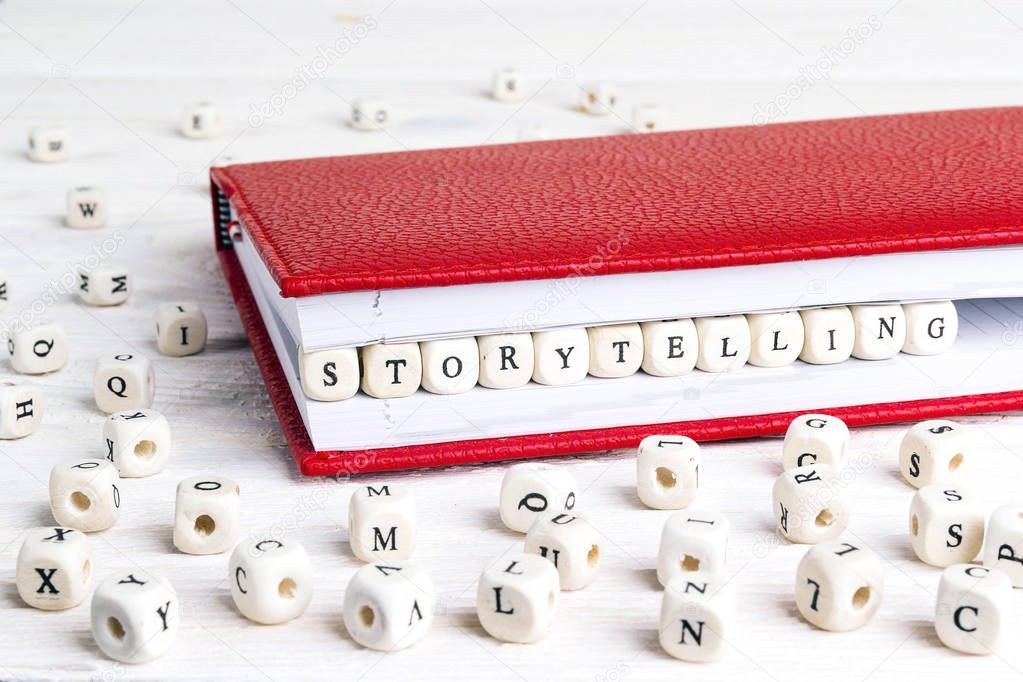 Word Storytelling  written in wooden blocks in red notebook on w