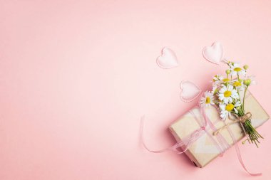 Chamomiles pembe bir arka plan üzerinde hediye kutusu ile küçük bir grup. Uzay kopyalayın. Üstten görünüm.