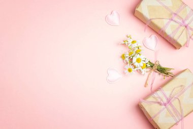 Küçük grup chamomiles hediye kutuları üzerinde pembe bir arka plan ile. Uzay kopyalayın. Üstten görünüm.