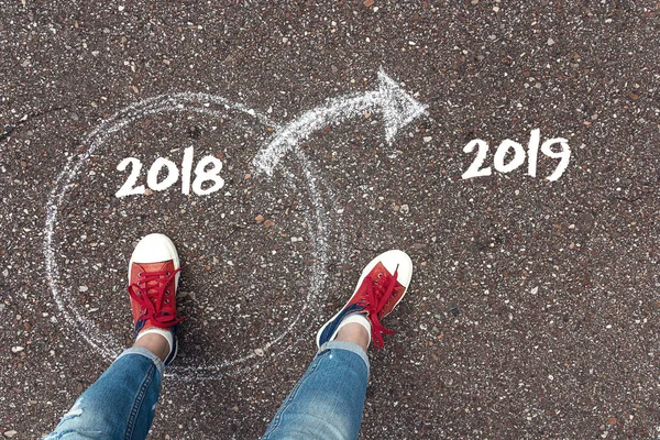 2019 の新しい年と古い年を残して起動します 2019 アスファルトにチョークで 2018 年円と外向き矢印中立っている赤いスニーカーの足 成功と通過時間の概念 — ストック写真