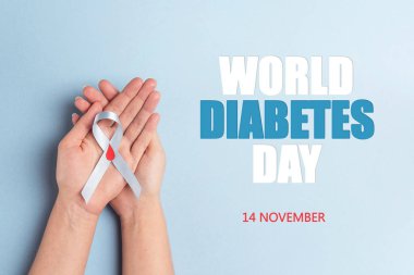 Mavi kurdele bilinci ile kırmızı kan holding yardımcı eller mavi bir arka plan üzerinde bırakın. 14 Kasım Dünya Diyabet günü. Kopya alanı, üstten görünüm.