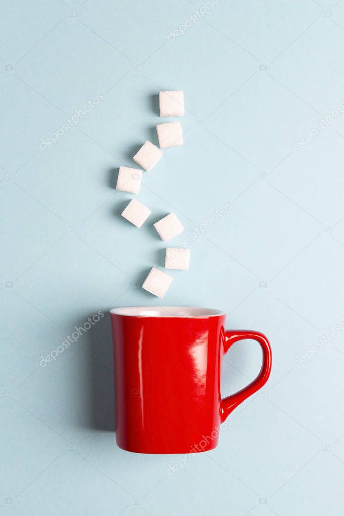 Red mug with sugar cubes on a blue background. Sugar addict. Diabetes concept.