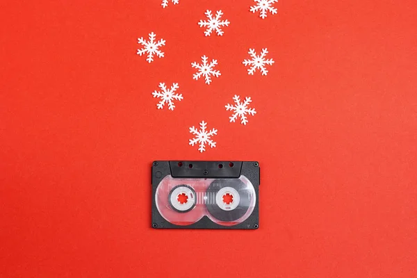 Audio cassette tape with decorative snowflakes on a red background. Music for Christmas mood. Nostalgia concept.