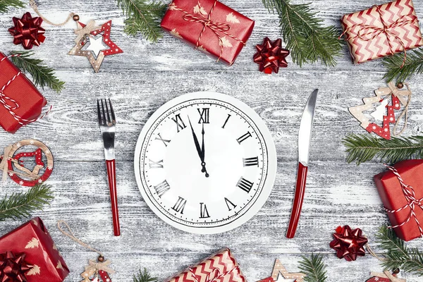 Festive table setting with dish clock and Christmas decorations on wooden table. Top-down Christmas  tableware composition on grey wooden background.