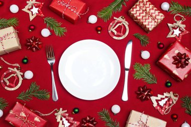 Çatal bıçak takımı ve kırmızı kumaş arka plan üzerinde Noel süslemeleri ile Festival tablo ayarı. Üstten görünüm. Noel sofra.