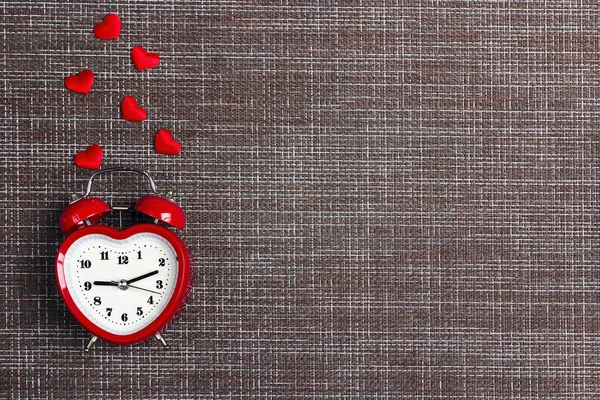 Heart-shaped alarm clock and hearts on sackcloth background. Place for text. Top view. Time for love and greetings.