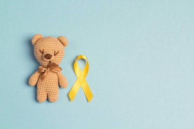 Çocuk oyuncak bir çocukluk kanseri bilinçlendirme sarı şerit üzerinde mavi arka plan ile. Çocukluk kanser günü, 15 Şubat.