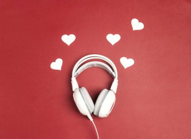 Kalp kırmızı zemin üzerine beyaz kulaklık. Romantik müzik konsepti. St Sevgililer günü kavramı. Düz yatıyordu, en iyi görünümü.