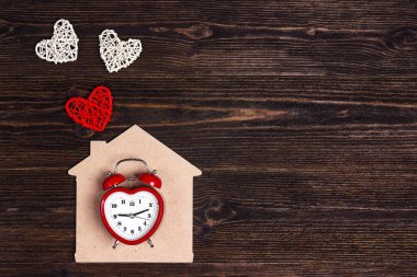 Çalar saat ile ev sembolü ve kalpleri ahşap arka plan üzerinde. Sevgililer günü kavramı. Üstten görünüm.