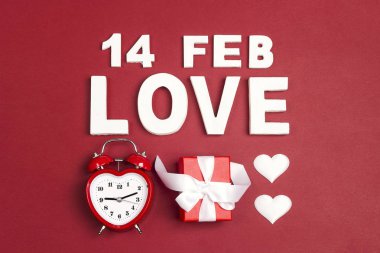 St Sevgililer günü kelime aşk, çalar saat, hediye ve dekoratif kalpler kırmızı arka plan. Yukarıdan aşağıya kompozisyon.