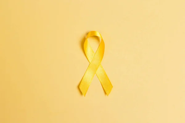 Childhood Cancer Awareness Yellow Ribbon on yellow background. Childhood Cancer Day February, 15.