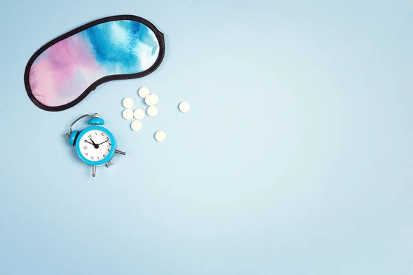 Schlafmaske, Pillen und Wecker auf blauem Hintergrund. Gesund — Stockfoto