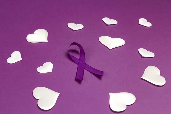 Purple epilepsy awareness ribbon wit white heats on a purple bac
