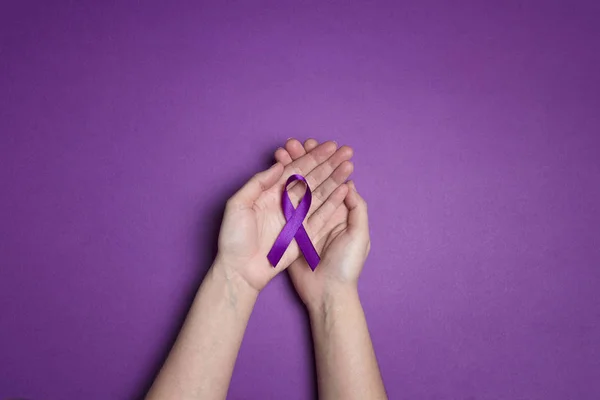 Hands holding Purple ribbons on a purple background. World epile