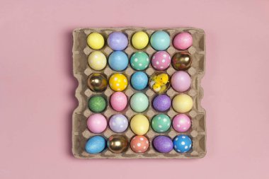 Birçok Paskalya yumurtaları tepsi üzerinde pembe bir arka plan üzerinde renkli. 