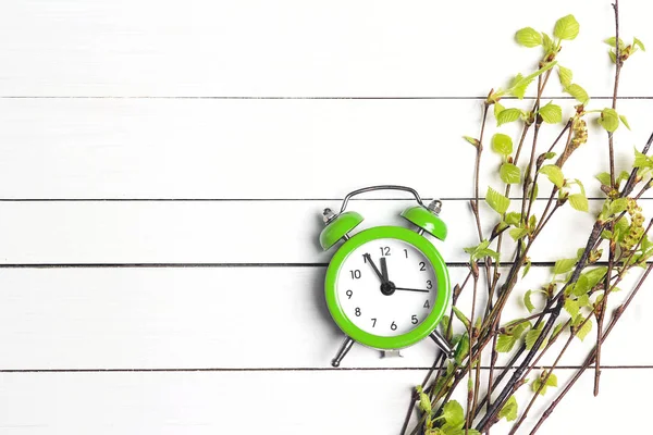 Reloj despertador verde y ramas de abedul joven con las primeras hojas y —  Fotos de Stock