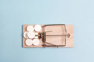 Mavi bir arka plan üzerinde ahşap fare kapanı içinde ilaç. 