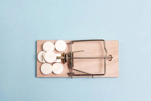 Medicines in a wooden mouse trap  on a blue background. — Stock Photo, Image