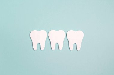 Mavi zemin üzerine beyaz kağıt diş. Diş sağlığı kavramı. FLA