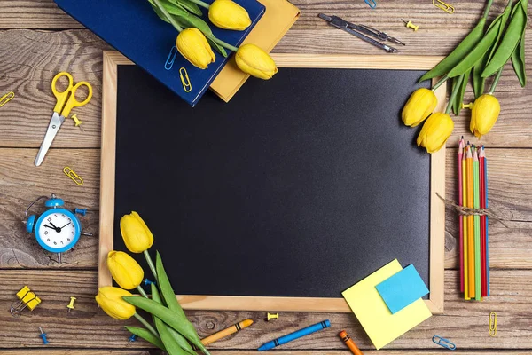 Una pizarra con útiles escolares y flores de tulipán en un rústico —  Fotos de Stock