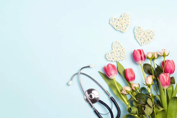 Cambada de tulipas e rosas com estetoscópio sobre fundo azul. T — Fotografia de Stock