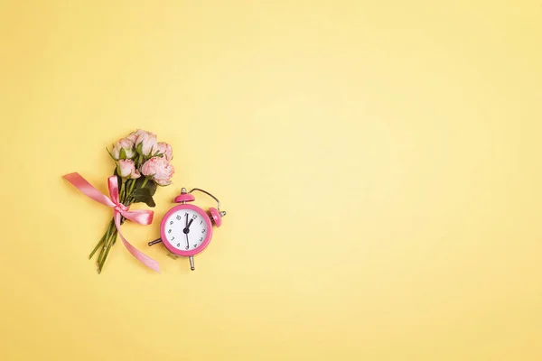 目覚まし時計と花束を持つお祝いのトップダウン黄色の背景 — ストック写真