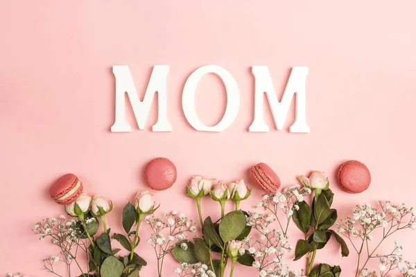 Small white flowers and roses with macarons and word Mon on pink — Stock Photo, Image