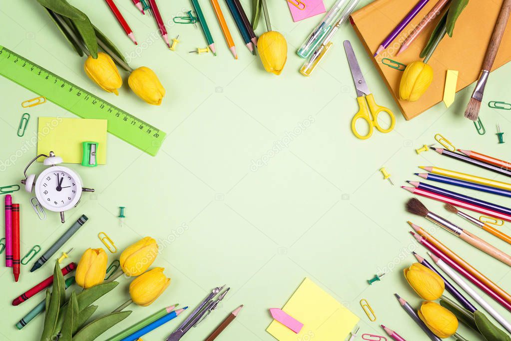 Flat lay frame composition from school supplies and yellow tulip
