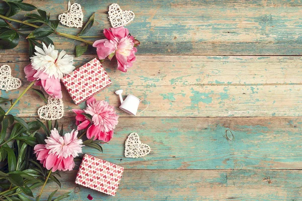 Feestelijke achtergrond met roze pioenrozen, cadeaus en harten op een oude — Stockfoto
