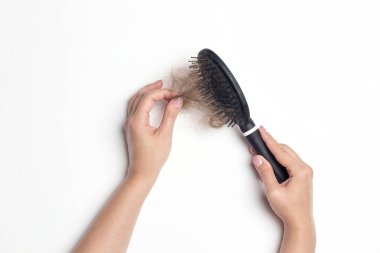 Düşmüş saçlı tarak ile kadın elleri. Saç dökülmesi sorunu.