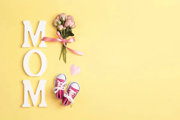 Word mom with pink baby girl sneakers and small bouquet of roses — Stock Photo, Image