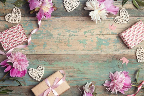 Feestelijke frame van roze pioenrozen, geschenken en harten op een oude Turqu — Stockfoto