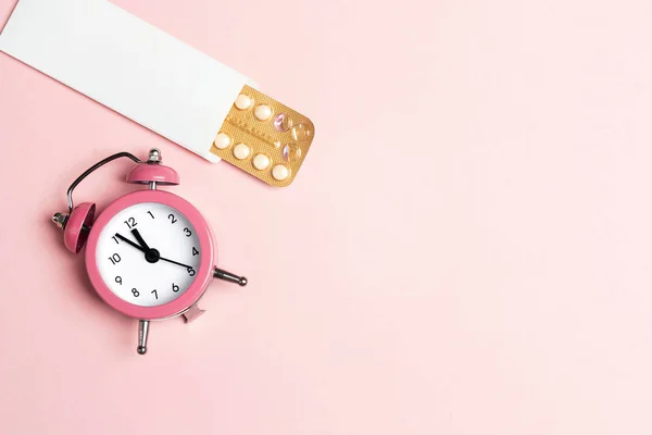 Mulheres pílulas contraceptivas orais blister com despertador no rosa — Fotografia de Stock