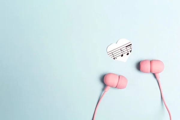 Fones de ouvido rosa com coração de música em fundo azul e copiar spac — Fotografia de Stock