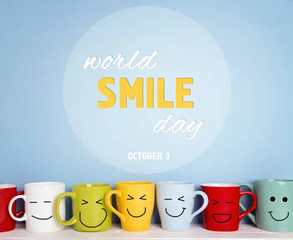 Welt Lächeln Tageskarte mit bunten Tassen auf blauem Hintergrund. — Stockfoto