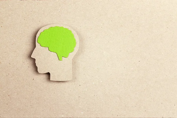 Силуэт головы человека с зеленым мозгом на бумажном фоне — стоковое фото