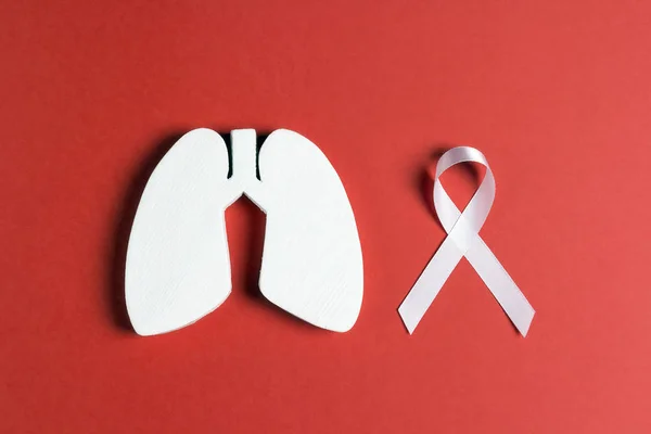 White lung cancer awareness ribbon and lung symbol on red backgr
