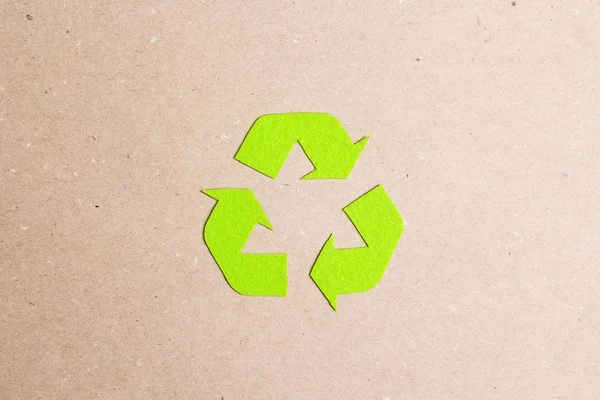 Green arrows recycle eco symbol on brown paper background.