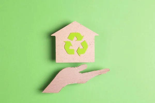 Ekologiskt hus med återvinningssymbol på papphand siluett — Stockfoto
